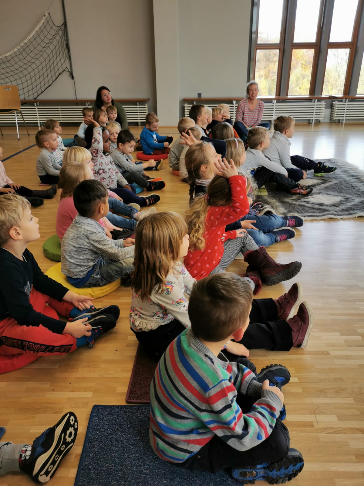 Kindergartenkinder auf Sitzkissen lauschen gespannt dem Märchenerzähler im Klubhaus Seebach.