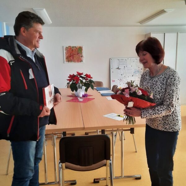 Bürgermeister Gerrit Häcker überreicht Inge Schröder Blumen und ein Geschenk zum 45-jährigen Dienstjubiläum